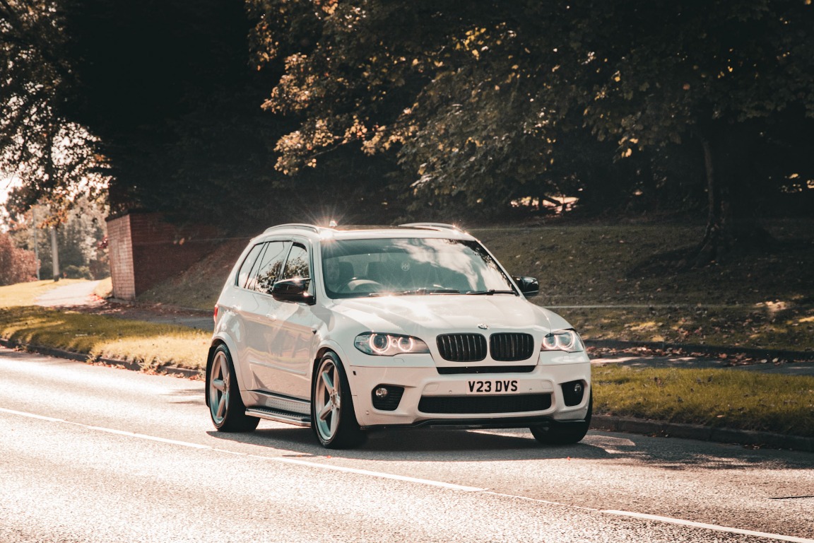 A white BMW photographed in warm evening sunlight on a quiet road.
