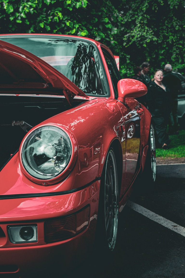 A vivid red Porsche parked outdoors with dramatic lighting.
