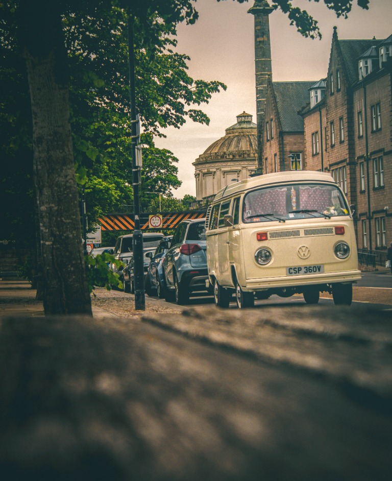 A VW campervan at a classic car gathering with colourful tents nearby.