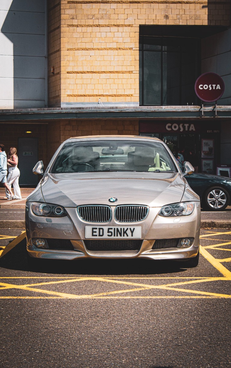 Front three-quarter view of a silver BMW coupe in a city centre car park.