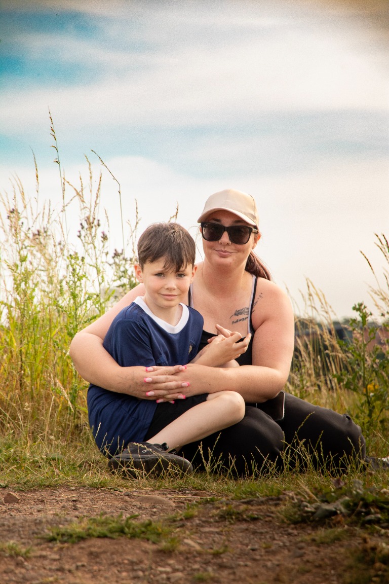 A mother and child share a relaxed portrait among tall grasses.
