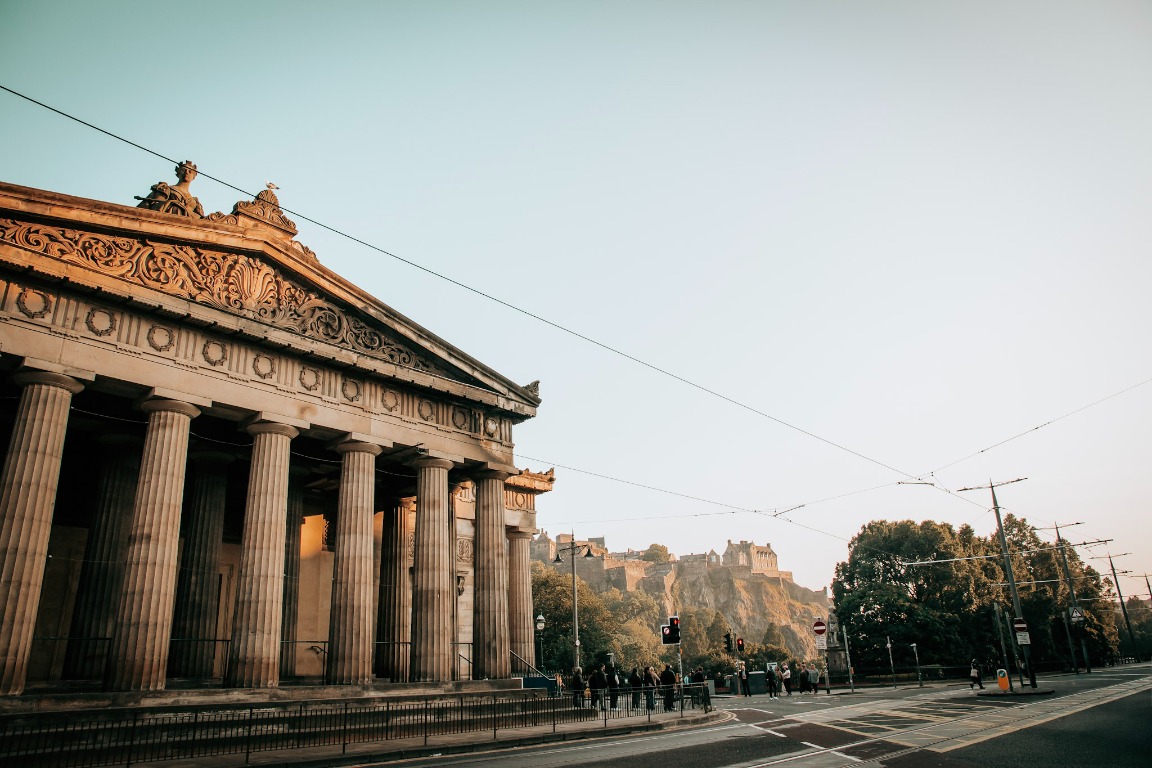 A grand stone building and city street in warm evening light.