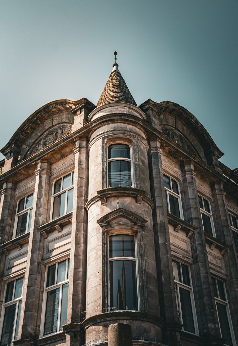 Upward view of an ornate stone building and turret against the sky.